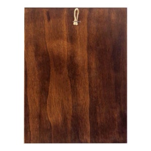 May include: A dark brown wooden plaque with a small loop of twine attached to the top.