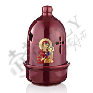 May include: A red ceramic oil lamp with a cross and a star design. The lamp features a depiction of the Virgin Mary holding baby Jesus.