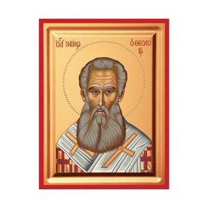 Op de afbeelding: Een rechthoekig religieus icoon met een portret van een bebaarde man met een aureool tegen een gouden achtergrond. De figuur draagt wit-gouden gewaden met rode kruispatronen. De Griekse tekst O Agios Theologos staat bovenaan vermeld.