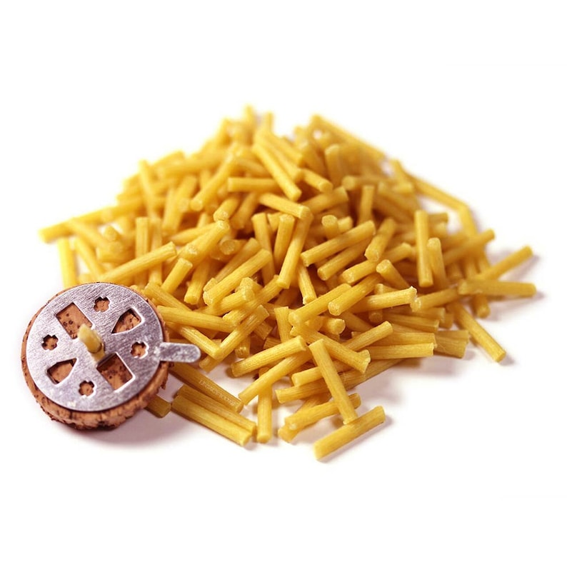 May include: A pile of yellow wax sticks for use in a shisha pipe, next to a metal shisha bowl with a cork base.