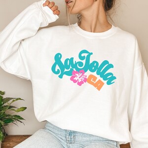 May include: White sweatshirt with a turquoise graphic that says "La Jolla CA" with a pink hibiscus flower.