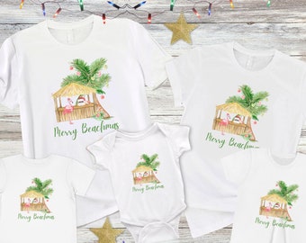 May include: White t-shirts and a onesie with a watercolor design featuring a beach hut, palm tree, and flamingo. The text "Merry Beachmas" is printed in green. Festive holiday apparel.