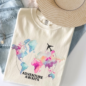 L'aventure vous attend, le cadeau du voyageur, les vacances, le confort, les couleurs, le T-shirt pour les amateurs de voyages, la carte du monde et le T-shirt en mode avion.