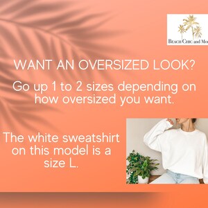 May include: Text graphic on a peach background with a palm tree logo that says "Beach Chic and More". The text reads "WANT AN OVERSIZED LOOK? Go up 1 to 2 sizes depending on how oversized you want. The white sweatshirt on this model is a size L."