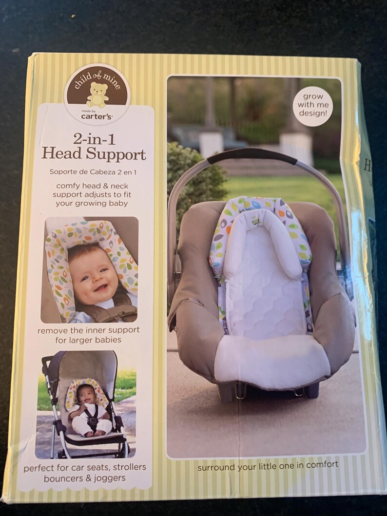 May include: A product packaging box for a 2-in-1 head support for babies. The box is yellow with green stripes and features a photo of the head support in use in a car seat and a stroller. The text on the box reads 'child of mine', 'carter's', '2-in-1 Head Support', 'Soporte de Cabeza 2 en 1', 'comfy head & neck support adjusts to fit your growing baby', 'remove the inner support for larger babies', 'perfect for car seats, strollers, bouncers & joggers', 'surround your little one in comfort', and 'grow with me design!'.