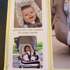May include: A baby head support for car seats, strollers, bouncers, and joggers. The support is made of soft fabric with a green and white leaf pattern. The support is adjustable to fit a growing baby. The text on the package reads 'comfy head & neck support adjusts to fit your growing baby', 'remove the inner support for larger babies', and 'perfect for car seats, strollers bouncers & joggers'.