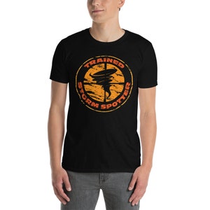 May include: Black t-shirt with an orange and black graphic of a tornado in a target circle. The text "Trained Storm Spotter" is around the circle.