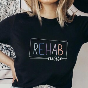 Peut inclure: T-shirt noir avec un cadre blanc autour du texte "REHAB nurse" en lettres colorées.
