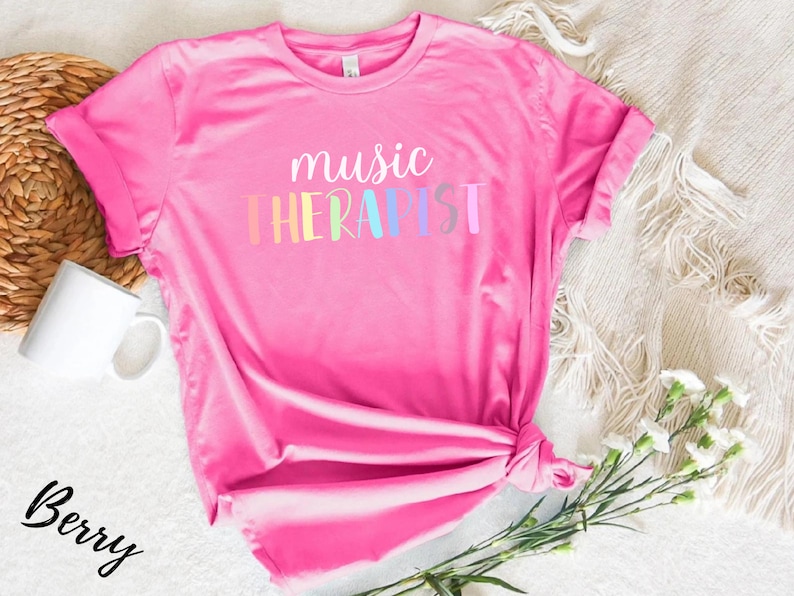 May include: Pink t-shirt with the text "music therapist" in rainbow colors.