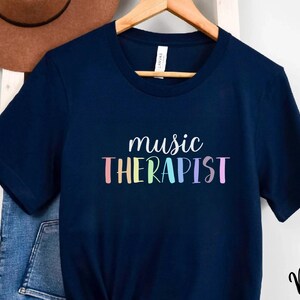 May include: A navy blue t-shirt with the text "music therapist" in rainbow colors.