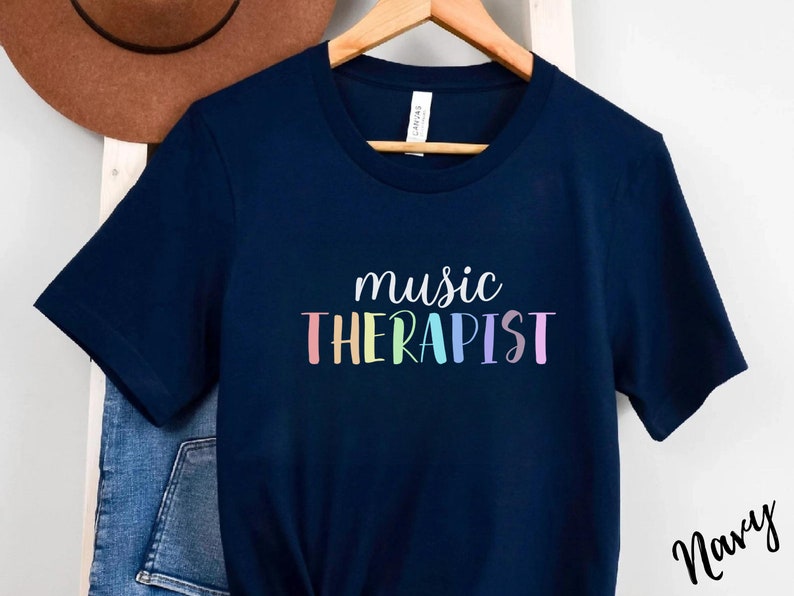 May include: A navy blue t-shirt with the text "music therapist" in rainbow colors.