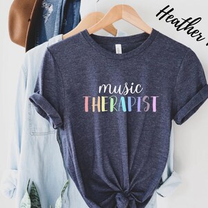 May include: A heather navy blue t-shirt with the text "music therapist" in rainbow colors.