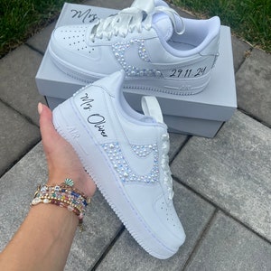 Puede incluir: Zapatillas blancas de cuero con una cinta de sat&eacute;n blanca atada alrededor del tobillo. Las zapatillas est&aacute;n decoradas con diamantes de imitaci&oacute;n y tienen el texto "Mrs. Oliver" escrito en el lateral. La fecha "29.11.24" est&aacute; escrita en el otro lado.