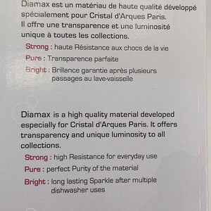 May include: A white label with the text "Diamax&reg; Made in France" in black. The label also features three overlapping circles in pink and gray with the words "Strong", "Pure", and "Bright" in red. The text below the circles describes the properties of the material Diamax, which is a high-quality material developed for Cristal d'Arques Paris.