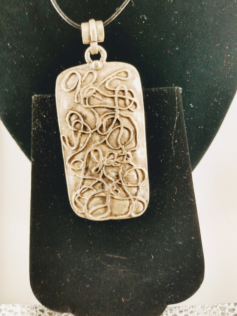 Metal scroll pendant with 18 inch leather chord