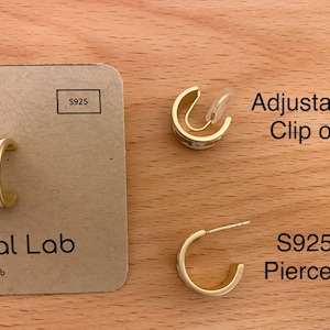 May include: Gold-toned hoop earrings featuring a white enamel surface with small orange and green floral motifs. The set includes an adjustable clip-on earring and a pierced earring with an S925 post, displayed on a tan card labeled Minimal Lab.