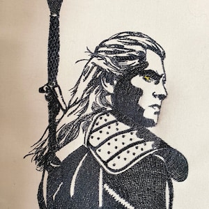 May include: Black and white embroidered image of a man with long hair, wearing armor and holding a sword. His eyes are highlighted in yellow.