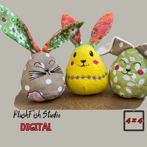Könnte beinhalten: Drei Plüsch-Osterhasen-Spielzeuge. Einer ist braun mit weißen Punkten, einer ist gelb mit einer rosa Nase und schwarzen Augen und einer ist grün mit weißen Blättern. Die Spielzeuge sitzen auf einer Holzoberfläche. PlushFish Studio DIGITAL 4x4