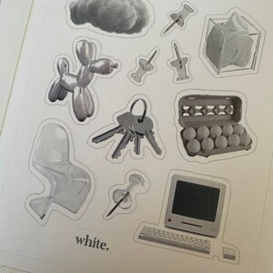 Puede incluir: Una hoja de pegatinas con varias im&aacute;genes en escala de grises, incluyendo una nube, un animal de globo, llaves, una silla, una computadora, una caja de huevos y chinchetas. El texto "white." est&aacute; impreso en la parte inferior de la hoja.