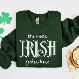 May include: A dark green sweatshirt with white text that reads "the most Irish fecker here".