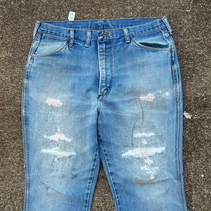 May include: A pair of light blue denim jeans with several distressed areas and a faded appearance. The jeans have a straight leg and a classic five-pocket design.