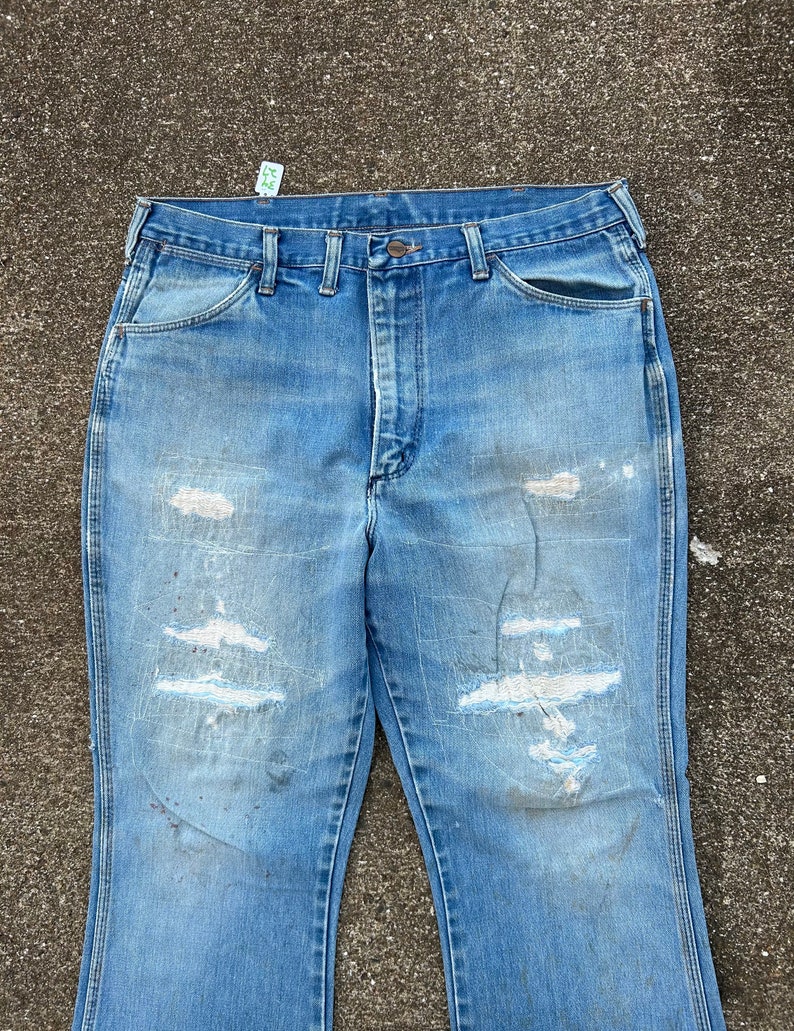 May include: A pair of light blue denim jeans with several distressed areas and a faded appearance. The jeans have a straight leg and a classic five-pocket design.