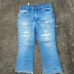 May include: A pair of light blue denim jeans with a wide leg and frayed hems. The jeans have several distressed areas and are faded in color.