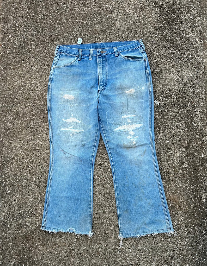 May include: A pair of light blue denim jeans with a wide leg and frayed hems. The jeans have several distressed areas and are faded in color.