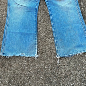 May include: A pair of blue denim jeans with a wide leg and frayed edges.