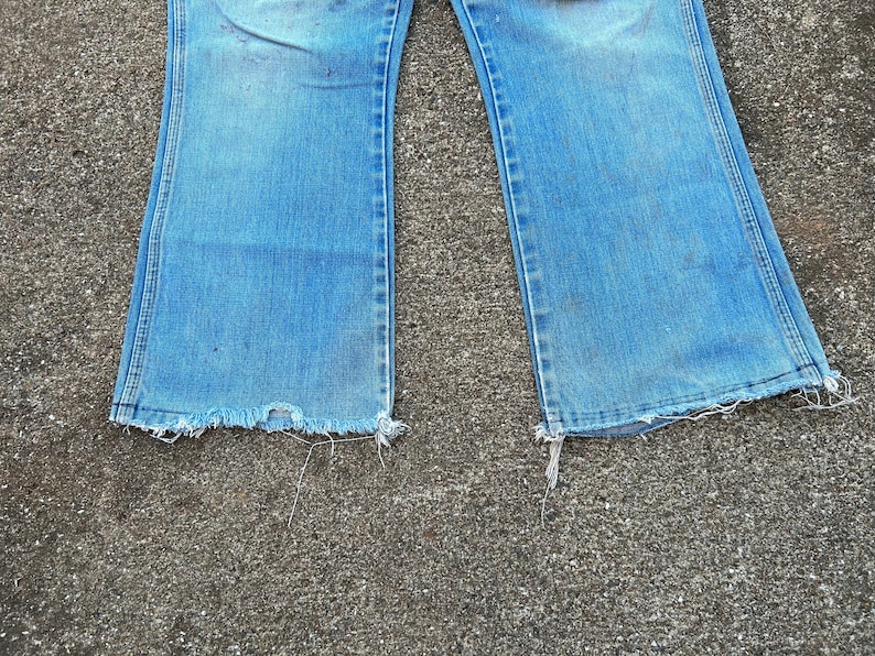 May include: A pair of blue denim jeans with a wide leg and frayed edges.