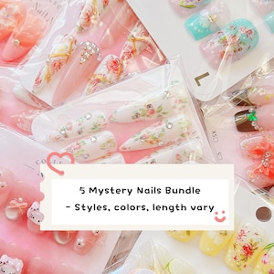 May include: A bundle of five sets of press-on nails in various styles, colors, and lengths, featuring floral patterns, rhinestones, and character designs. The packaging includes text reading 5 Mystery Nails Bundle - Styles, colors, length vary.