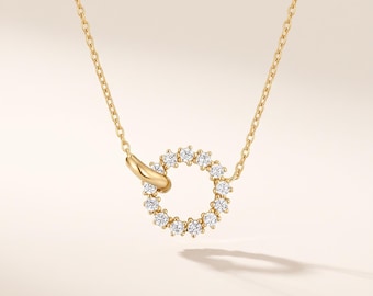 May include: A gold chain necklace featuring a circular pendant. The pendant consists of a smooth gold link connected to a circular frame set with twelve small, clear, round-cut stones arranged in a continuous circle around the center.