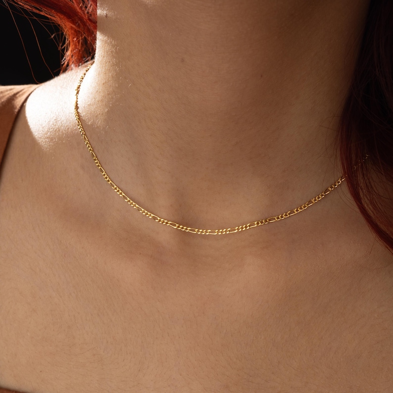 K&ouml;nnte beinhalten: Eine zarte goldene Kettenkette mit einem schlichten, klassischen Design. Die Kette ist d&uuml;nn und hat einen dezenten Glanz.