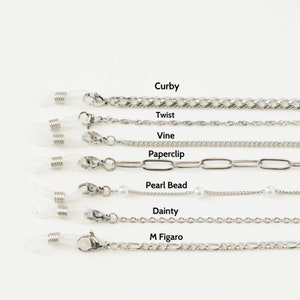 May include: A collection of silver-toned eyeglass chains with various designs, including Curb, Twist, Vine, Paperclip, Pearl Bead, Dainty, and M Figaro styles. Each chain features clear rubber loops for attaching to glasses and a clasp closure.