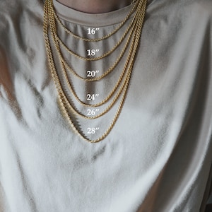 May include: A gold rope chain necklace is shown in different lengths, from 16 inches to 28 inches. The necklace is worn by a person with a light brown shirt.