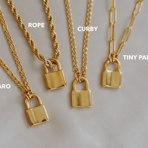 May include: Five gold necklaces with padlock pendants. The necklaces are on a white background. The necklaces are labeled: M-Figaro, Rope, Curby, Tiny Paperclip.
