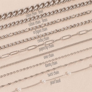 Op de afbeelding: Een close-up van tien verschillende zilveren kettingen, waaronder een kubaanse ketting, een m-figaro ketting, een curby ketting, een paperclip ketting, een wijnstok ketting, een delicate ketting, een gedraaide ketting en een parelketting. De kettingen zijn gelabeld met hun namen.