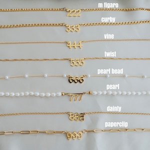 May include: Ten gold necklaces with different chain styles and pendant numbers from 222 to 999. The necklaces are arranged in a vertical row on a white background.