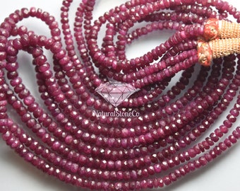 May include: Strands of faceted, deep red ruby beads. The beads are strung together, creating a layered effect. The image shows multiple strands of the ruby beads, with a gold and red tassel at the end.