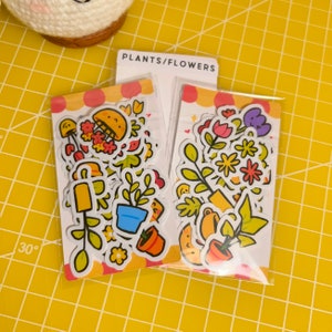 May include: Two sheets of stickers featuring colourful illustrations of plants, flowers, and gardening tools. The stickers are packaged in clear plastic and labelled "PLANTS/FLOWERS".