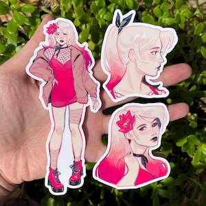 May include: Three stickers featuring a female character with pink and white hair. One sticker shows the full figure in a pink dress, jacket, and boots. The other two stickers are profile and portrait views of the character's face, with a flower in her hair.