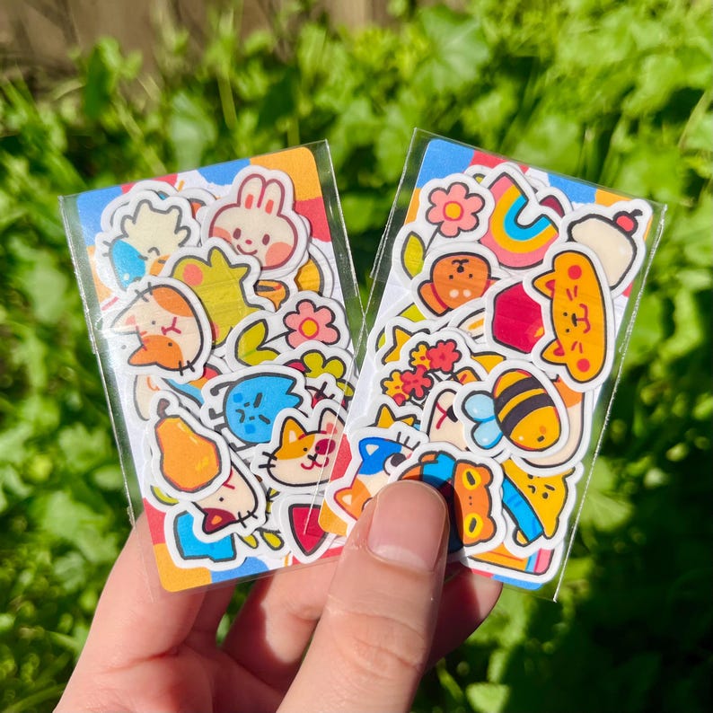 May include: Two sheets of colourful stickers featuring cartoon animals, flowers, and other cute designs. The stickers are on a white background and are perfect for adding a touch of whimsy to journals, planners, and other craft projects.
