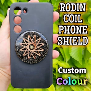 May include: A black phone case with a round, gold-coloured, decorative sticker featuring a copper wire coil design. The text "RODIN COIL PHONE SHIELD Custom Colour" is visible in the background.