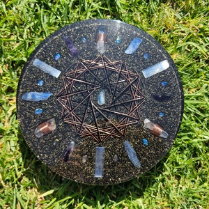 May include: A round, black resin tray with a copper wire grid pattern and various crystals embedded in the resin. The crystals are blue, clear, and purple.