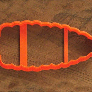 May include: Orange plastic cookie cutter shaped like a loaf of bread with a scalloped edge.