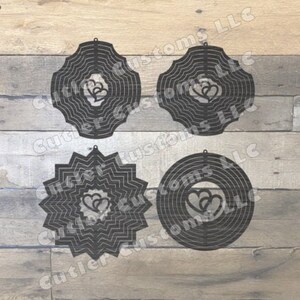 May include: Four black metal wind spinners featuring a double heart design. Each spinner has a unique shape and pattern.