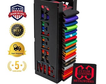 May include: A black metal vertical storage rack with the laser-cut text BEER ME on the front panel. The rack holds a stack of colourful foam beverage insulators. A single black foam insulator with the red text CUTLER CUSTOMS METALWORKS is shown.