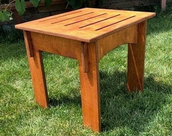 May include: A small, wooden table with a rectangular top and four legs. The table is made of light brown wood and has a natural finish. It is sitting on a green lawn.