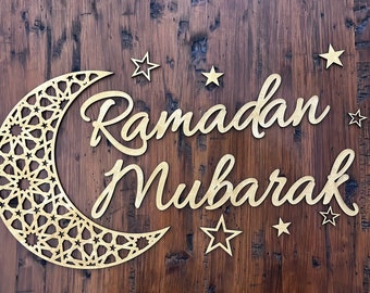 May include: A wooden sign with the words "Ramadan Mubarak" in a decorative script. The sign is decorated with a crescent moon and stars.