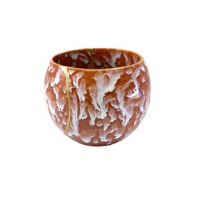 May include: A handcrafted, round ceramic bowl with a unique design. The bowl features a warm brown base color with white, flowing glaze patterns. A gold-colored line runs vertically, adding a touch of elegance. The bowl is ideal for serving or display.